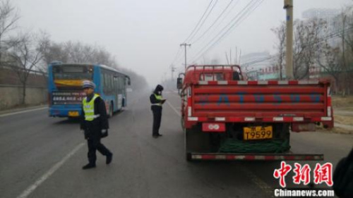 資料圖：2015年12月8日下午，京開(kāi)高速路輔路大莊橋路段，環(huán)境監(jiān)察人員檢查路上行駛的大貨車。張尼 攝